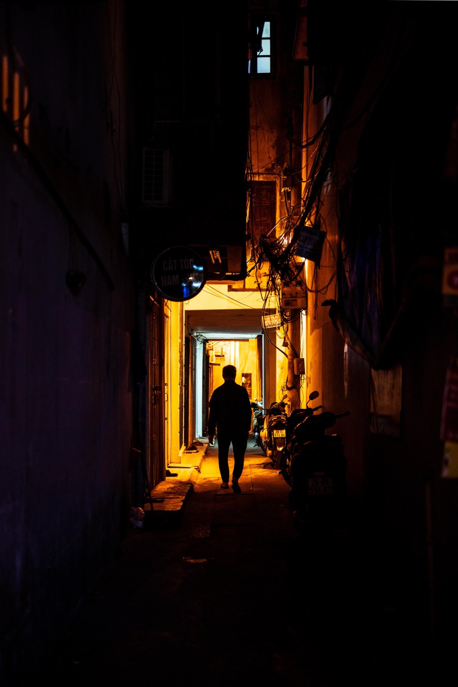Silhouette walking through a lit alleyway at night