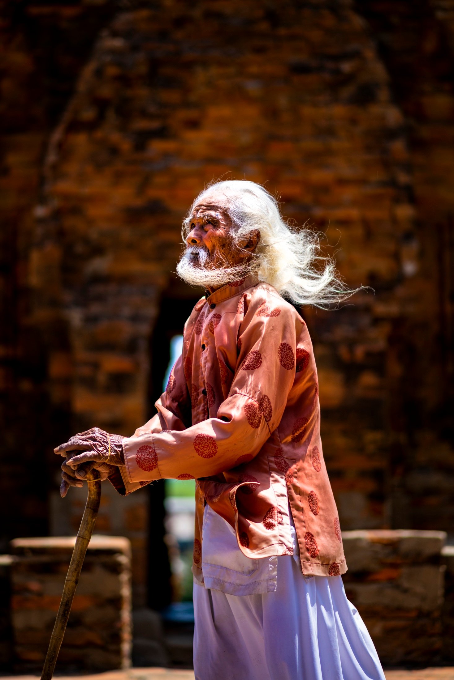 Elderly man in traditional dress, white hair and beard blowing in the wind